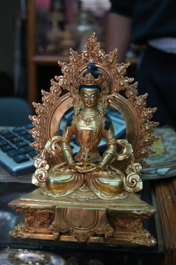 a buddha statue on a stand with keys next to a keyboard