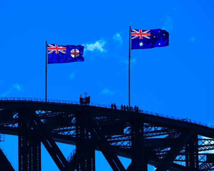 three flags are flying on the roof of a bridge