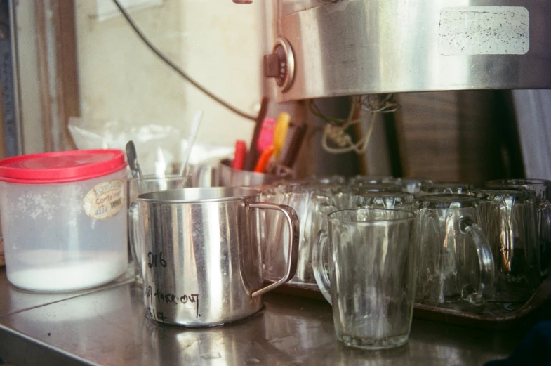 two mugs and six cups on a silver counter