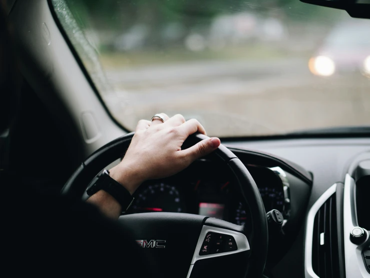 a person driving a car and pressing the wheel to press on the control on