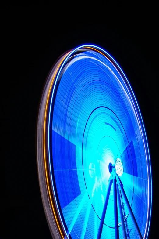 a ferris wheel at night with blue light in the dark