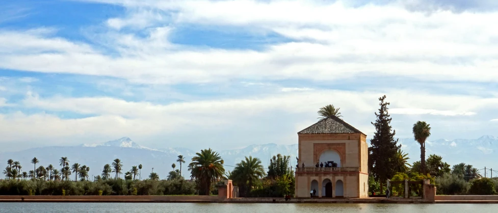 a clock tower in a body of water with a mountain range behind it