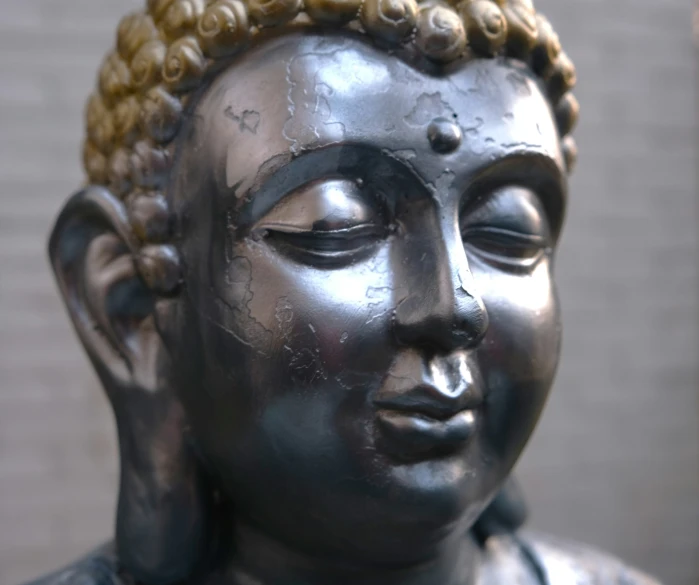 a statue with a silver head has gold beads on it