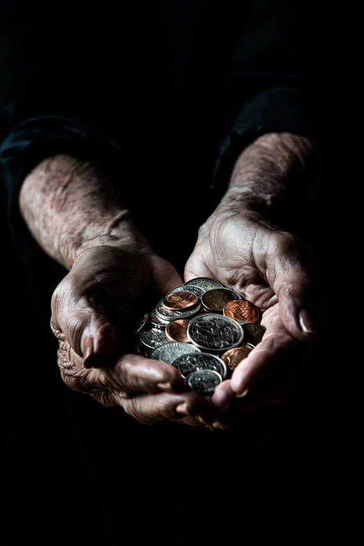 a close up of hands holding a handful of coin