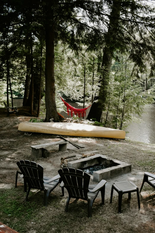 three empty lawn chairs and two campers, are sitting next to a canoe