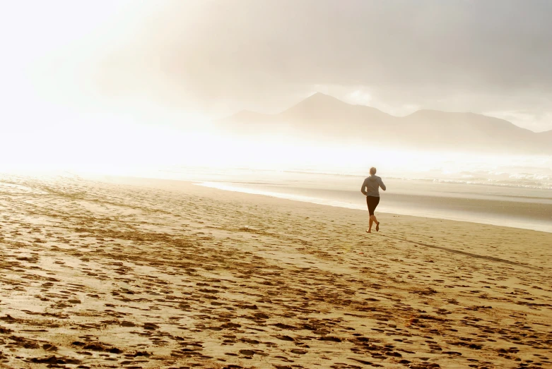 a person running down the beach in a light