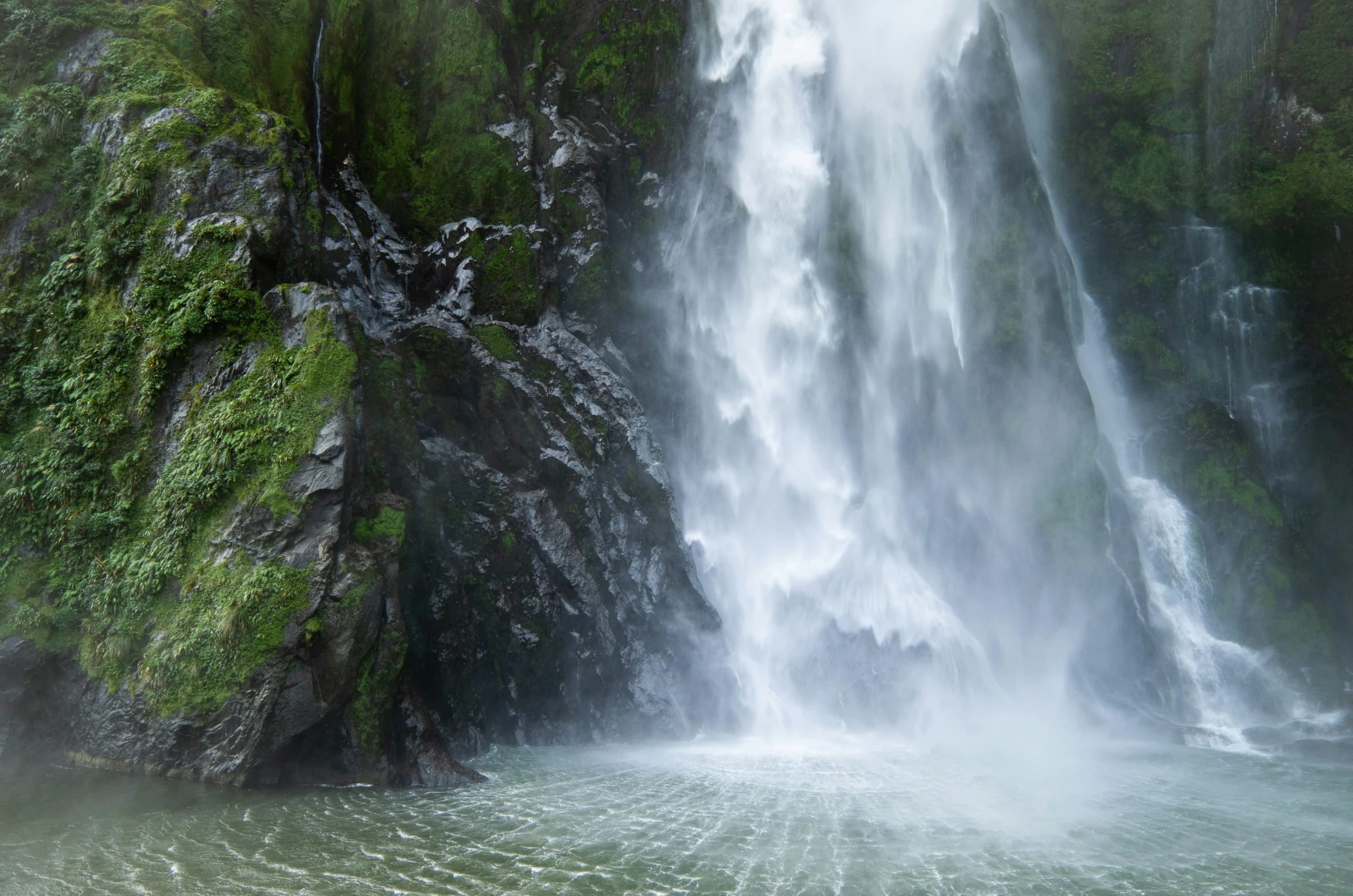 water fall coming from the large waterfall in front of a cliff