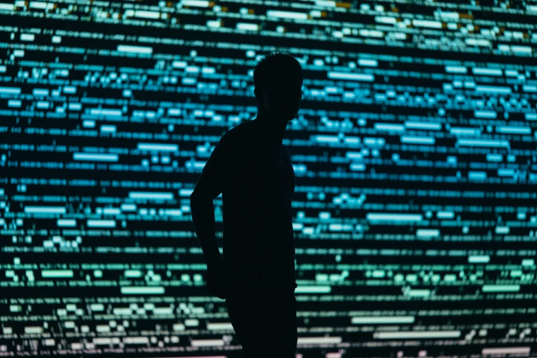 a silhouette of a man standing in front of a large display