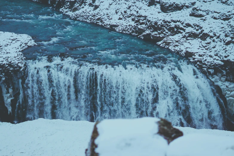 a snow - covered view of the water falling from an waterfall