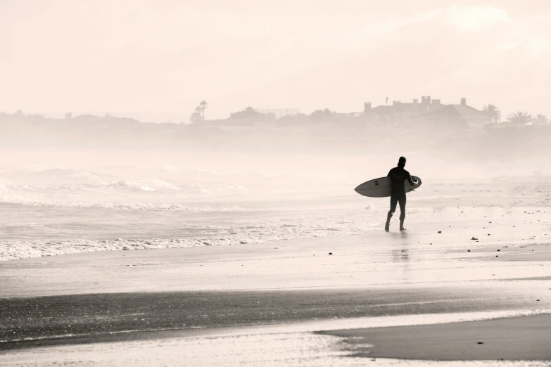 a person with a surfboard walking on the beach