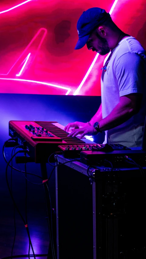 a dj mixing at his electronic device in front of neon lights
