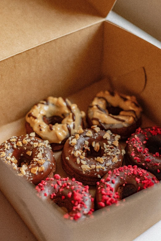 an open cardboard box with various donuts inside