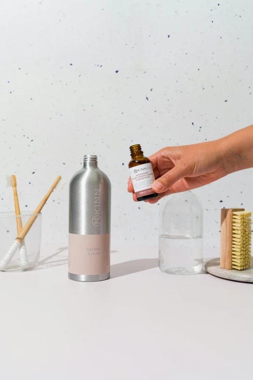 a person holding a bottle and some brushes and combs