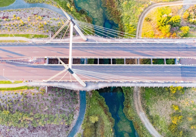 an aerial view of a bridge spanning over trees and a river