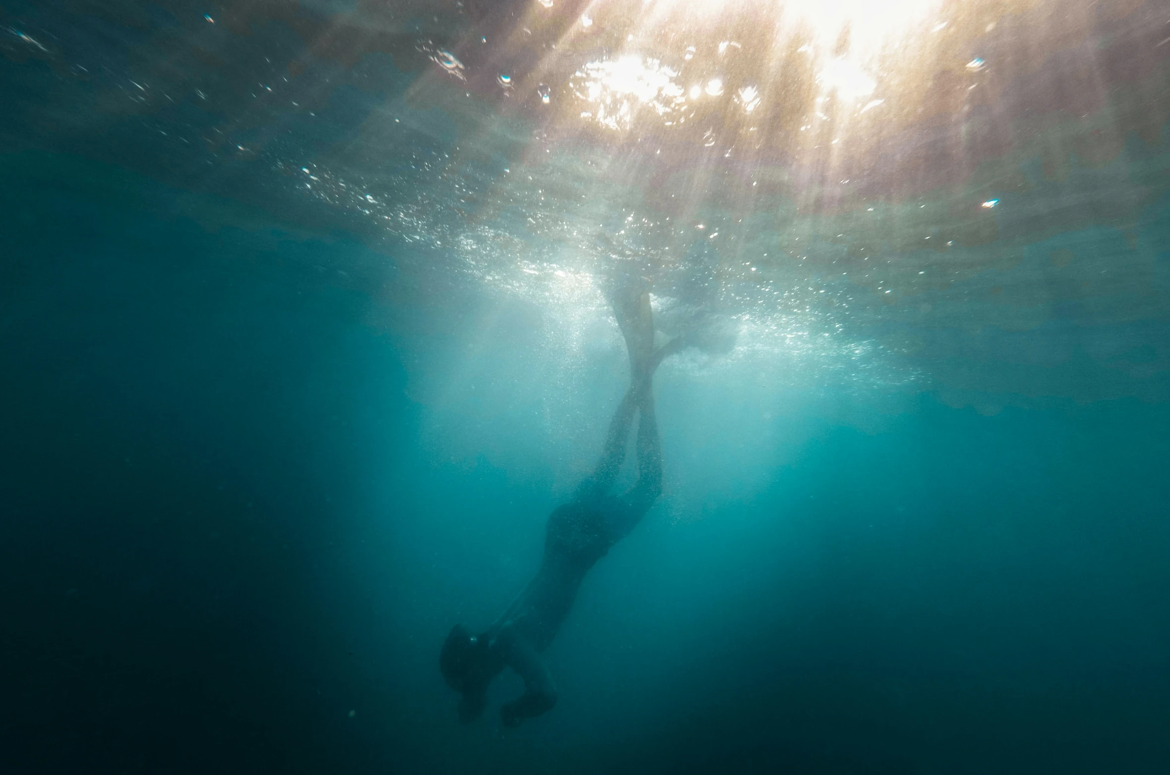 a person swimming in the water with the sun coming out