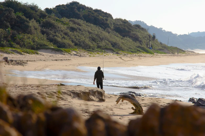 a man walking up to the water on a beach