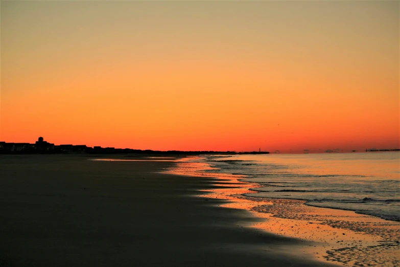 a beach near the ocean at sunset with people walking