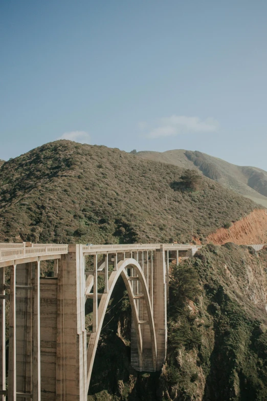 a large bridge over a mountain with a train on the bridge