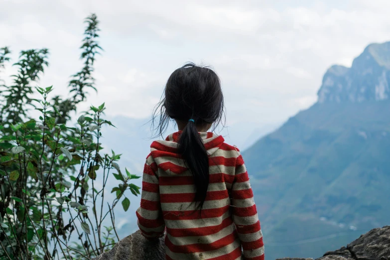 a  in striped shirt looking over mountain side