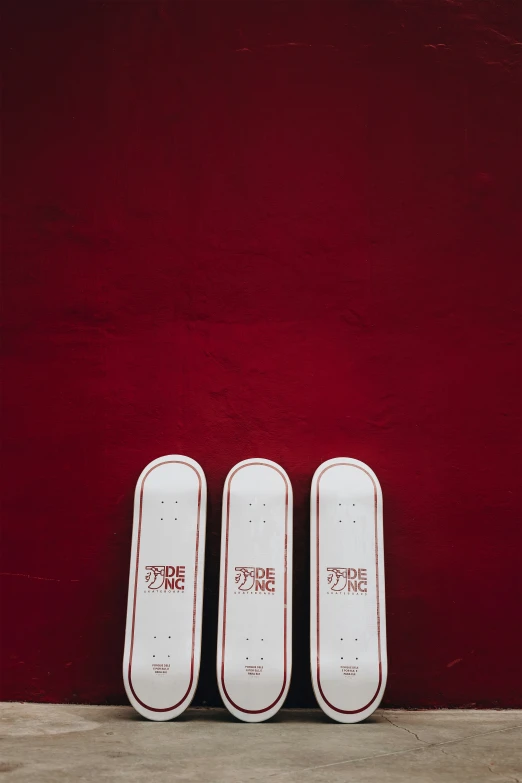 three skateboards are in front of a red wall