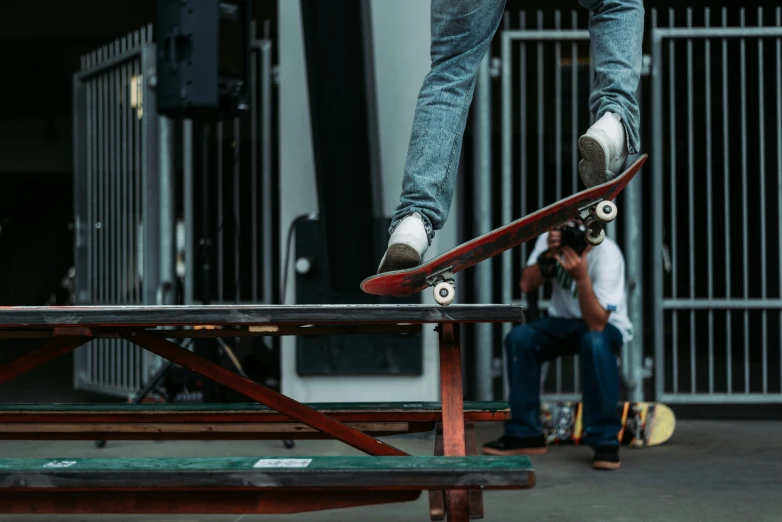 a young man doing tricks on his skateboard while another  looks on