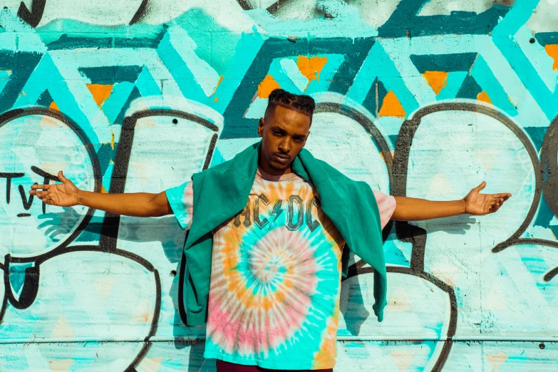 a man leaning against a colorful wall with his arms out