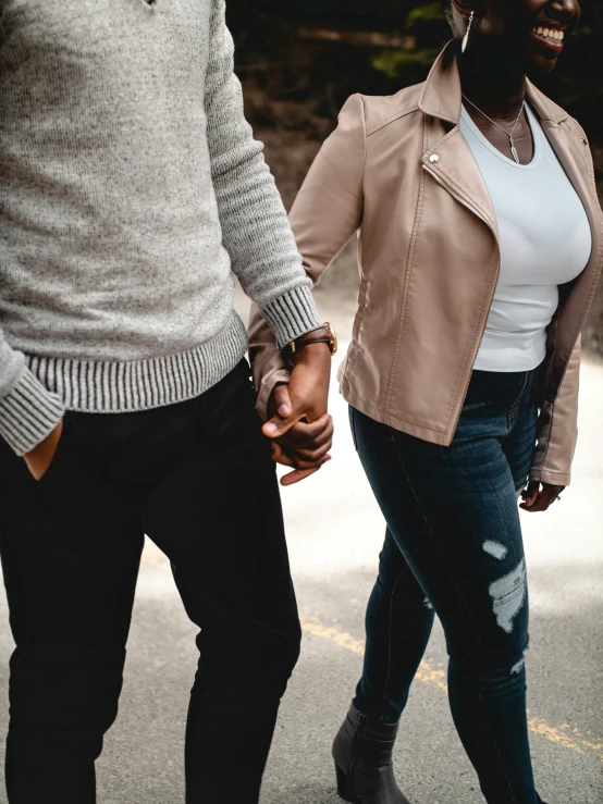 the man and woman hold hands while walking in the street