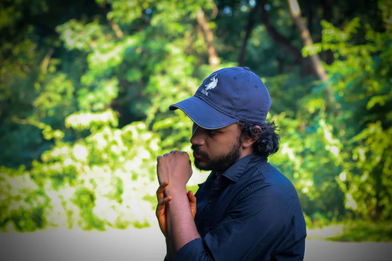 a man with a baseball cap on and arm folded in prayer