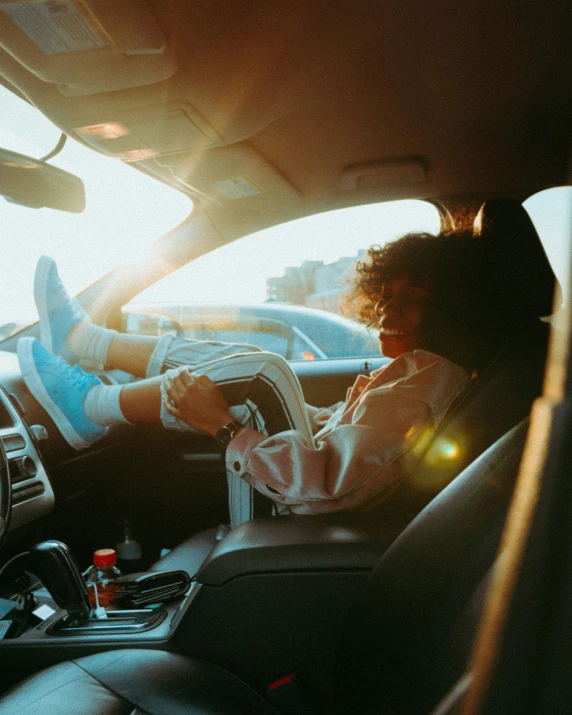 a woman in the driver seat with her feet on the dashboard of her vehicle