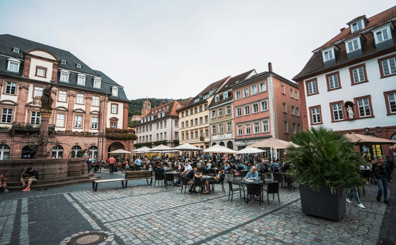 a crowd of people sitting at tables in a town square