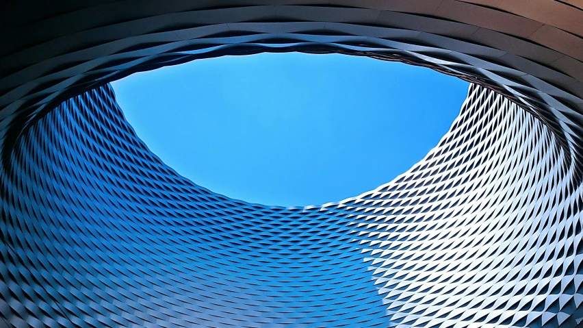 the view inside the circular structure in the building shows curved lines and blue sky