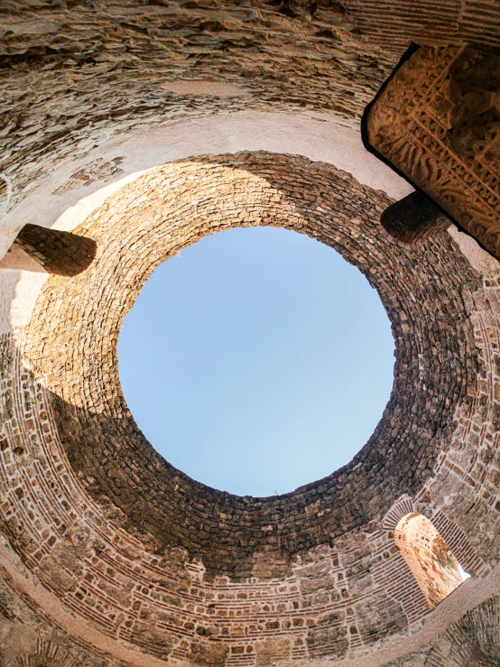 a very old round brick building with sky reflection