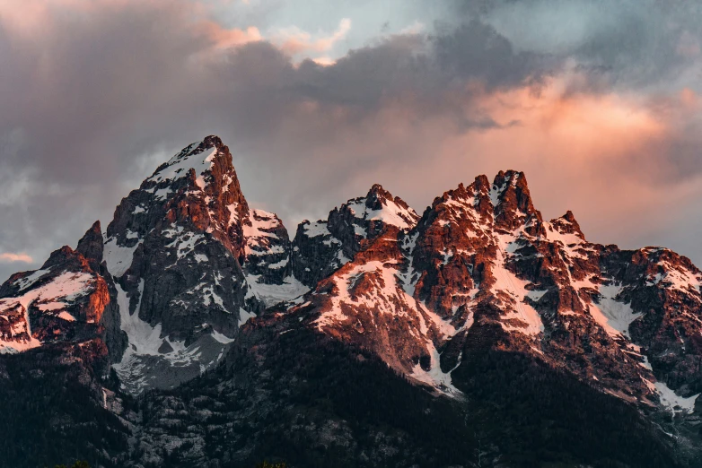 mountains covered in snow under a sky filled with clouds