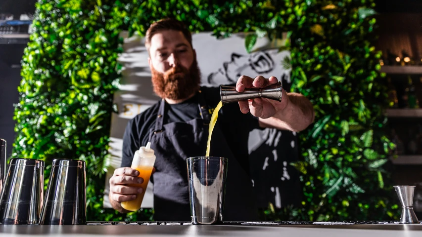 a bartender pours a bottle of beverage into an empty glass