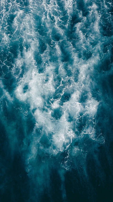 a large wave rolls over the ocean and a boat sits by