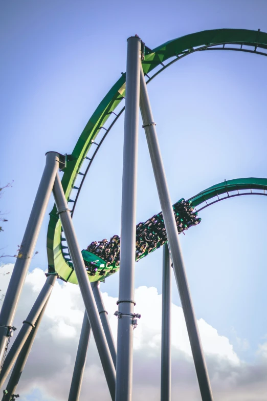 a green and blue roller coaster is in the air