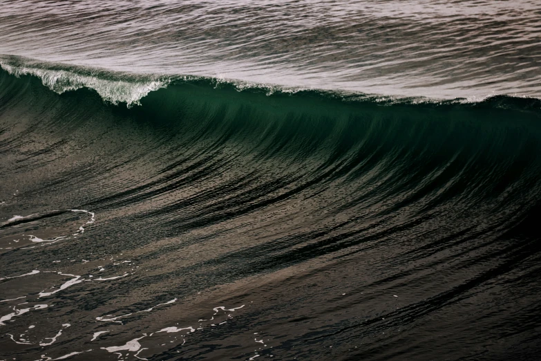 a wave crashing onto shore in front of some water