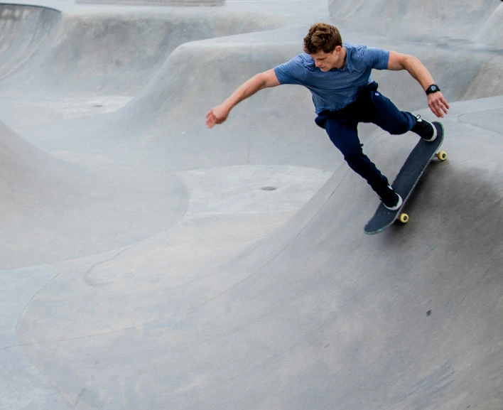 a man in blue shirt doing a trick on skateboard