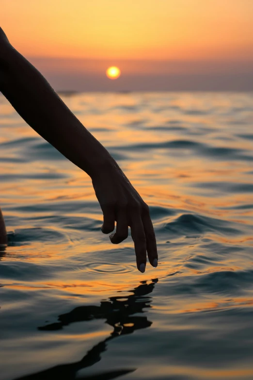 a person reaching for soing with their hand in the water