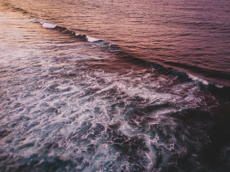 ocean waves breaking on the beach during sunset