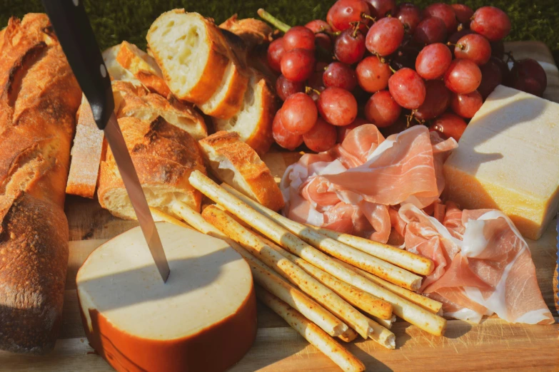 some breads, tomatoes, meat and gs on a board