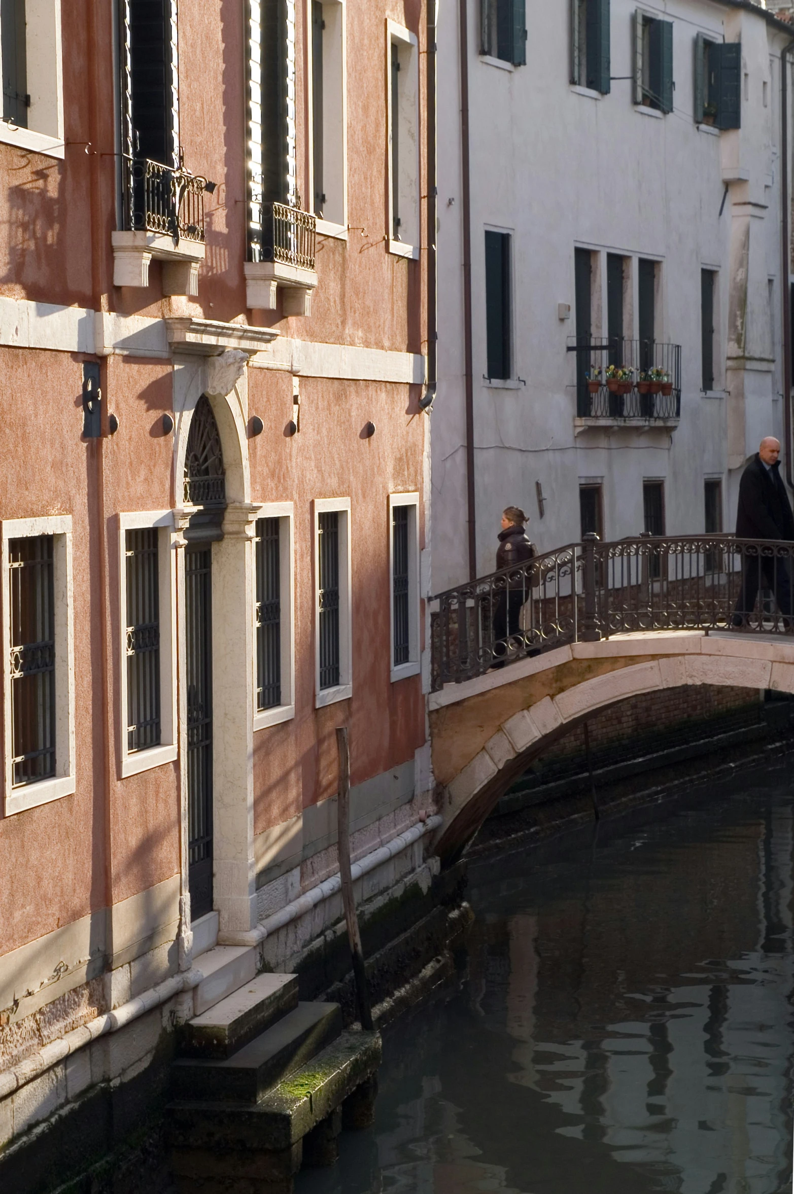 the bridge that is leading to an apartment complex has three balconies and a small balcony above