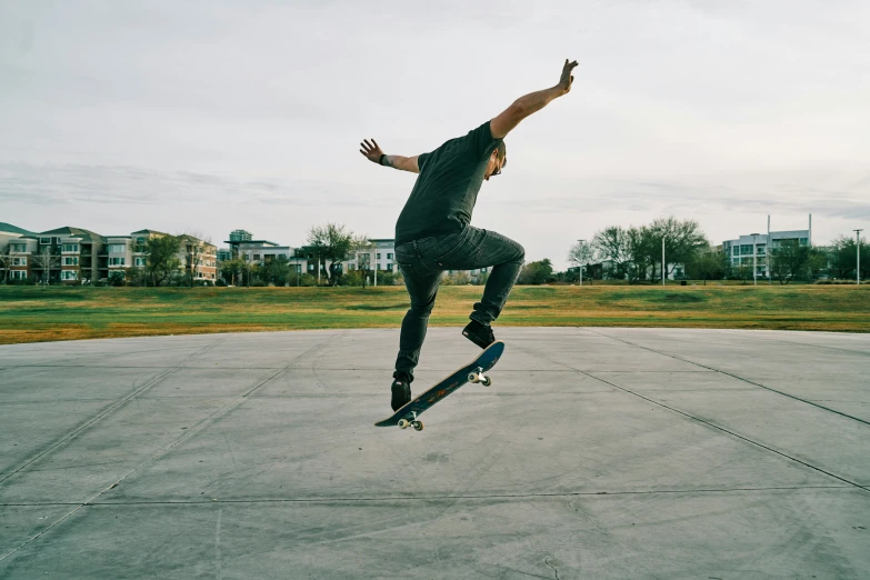 skateboarder in black performing trick on concrete area