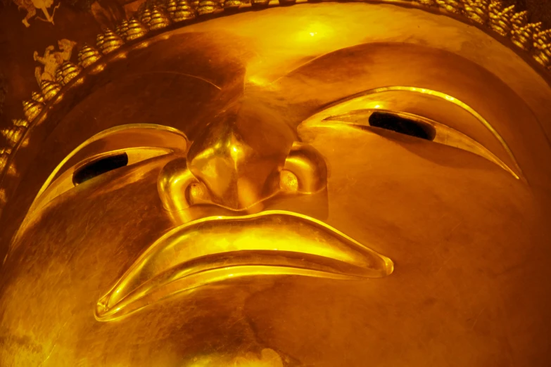 a gold mask of buddha being painted in the form of a bird