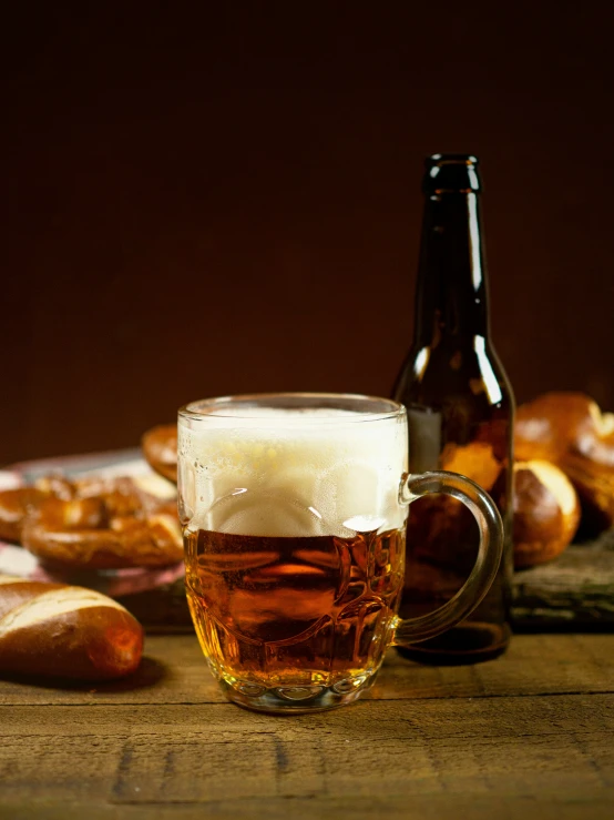a glass of beer next to a bottle of beer and buns