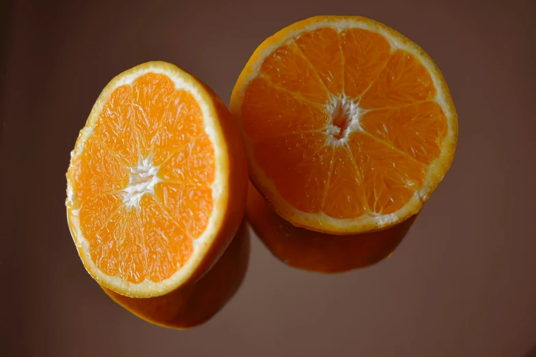 the two halves of a ripe orange are shown on a brown surface