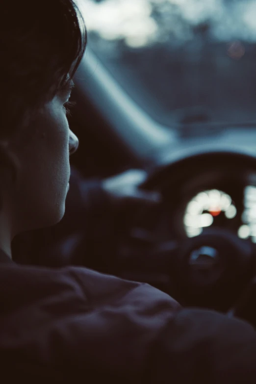 a young man sits inside a car next to the steering wheel