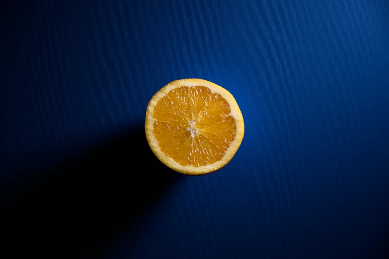 an orange on blue with shadows from the slice