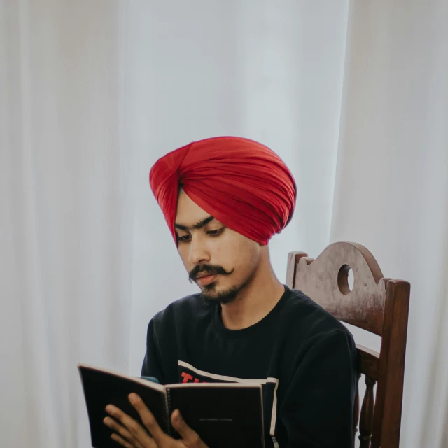 a man wearing a turban reading a book