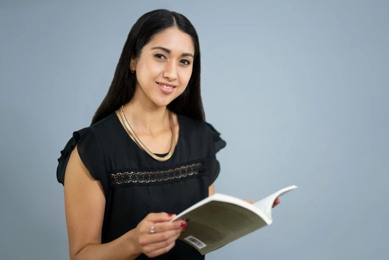 a woman smiling while holding out a book